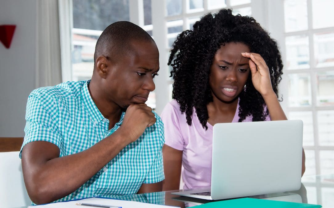 An image of a concerned couple staring at a laptop
