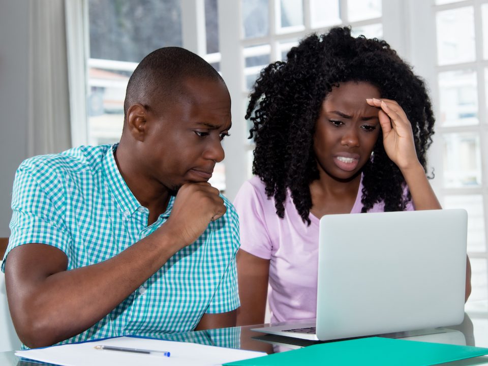 An image of a concerned couple staring at a laptop