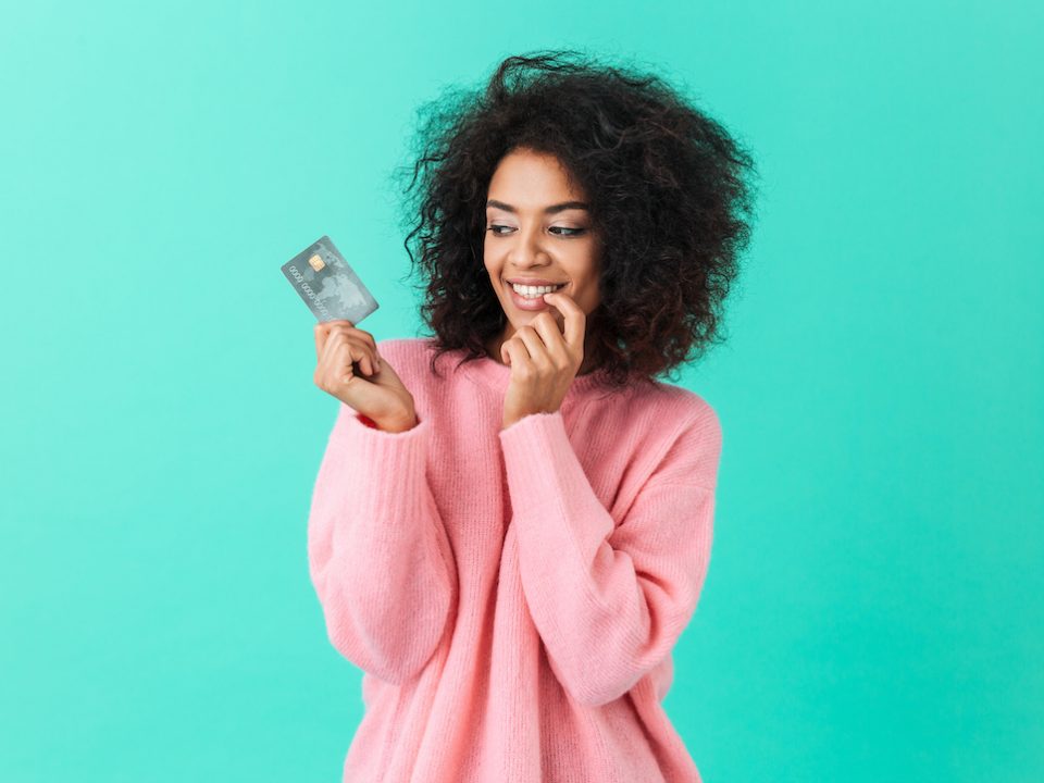An image of a woman smiling at her credit card.