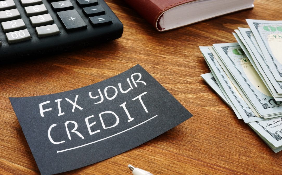 A black piece of paper with the words "Fix your credit" written in white pen.