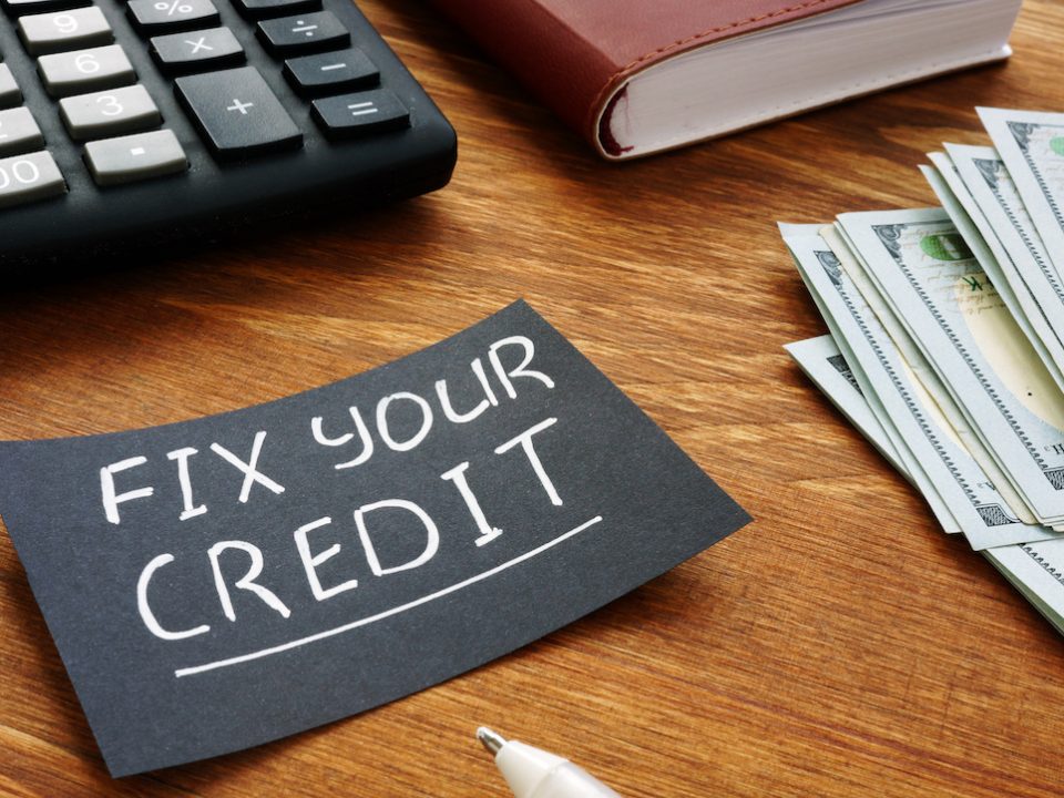 A black piece of paper with the words "Fix your credit" written in white pen.