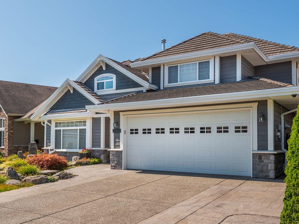 A dark blue house with a wide garage and neatly manicured lawn.