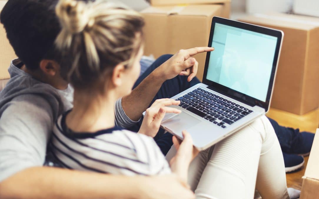 A pair of young people gesture to information on a laptop.