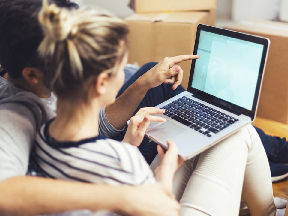 A pair of young people gesture to information on a laptop.