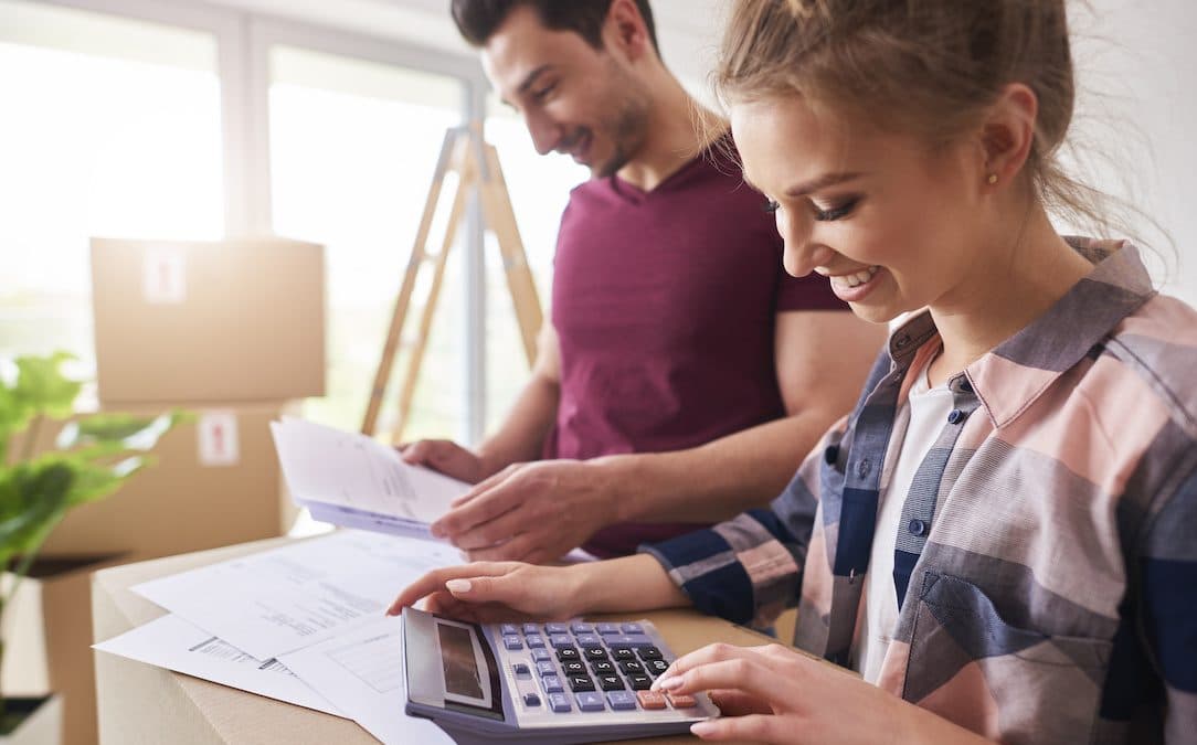 An image of two people moving into a house, doing quick sums on a calculator.