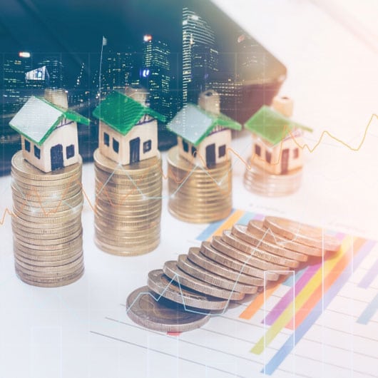 An image of toy houses balancing a rising stack of quarters.