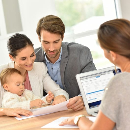 An image of couple with a child smiling over documentation.