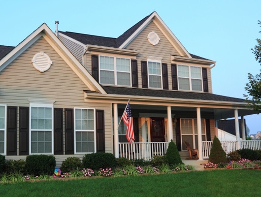 A classic, colonial style home with a wide, green lawn.