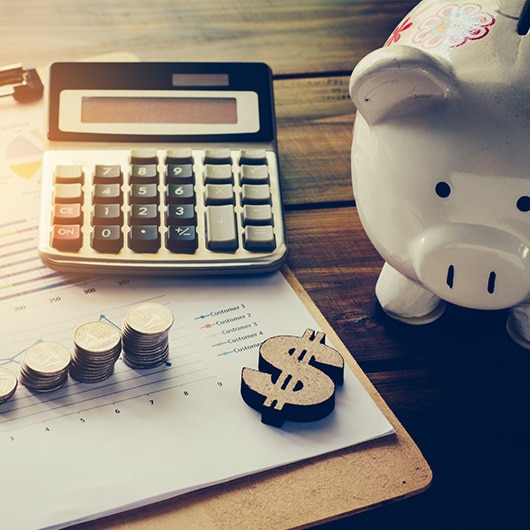 A piggy bank next to financial documents and a calculator.