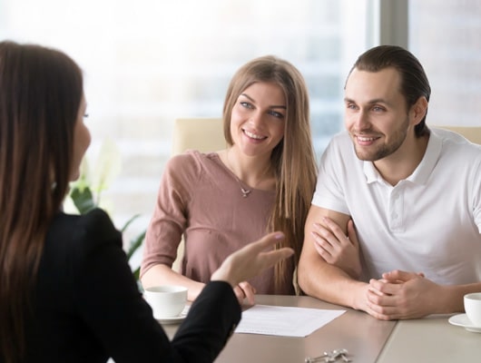 A couple smile while speaking with a lender.