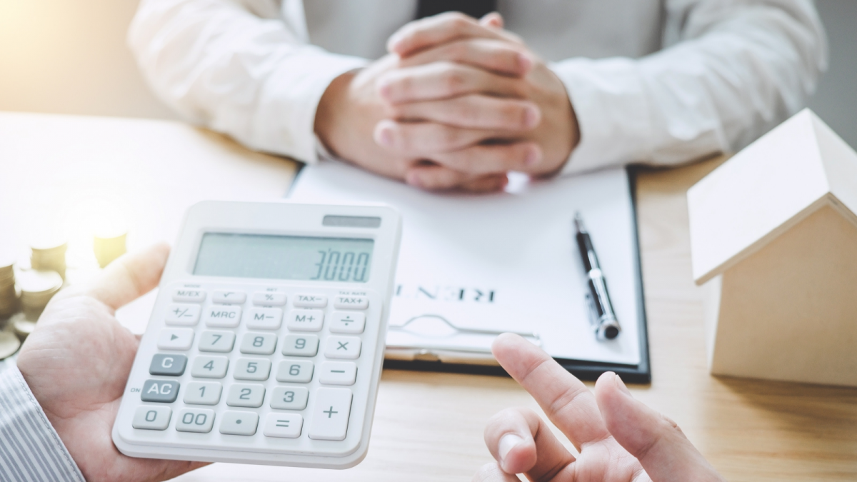 An image of a person gesturing to a calculator while talking with someone.