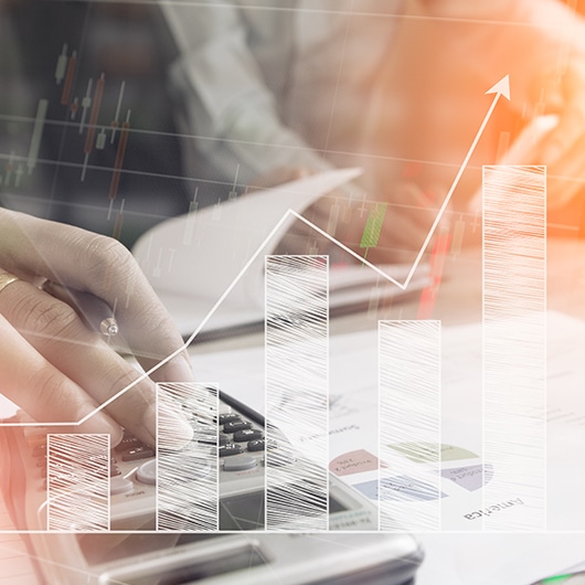 An overlay of a rising trend bar graph sits on top of an image of someone operating a calculator