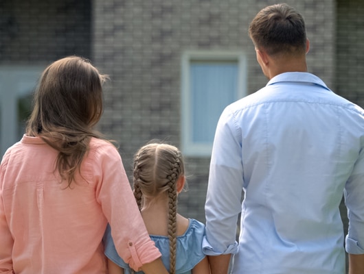 A family stand with their backs to the camera, looking in the distance.