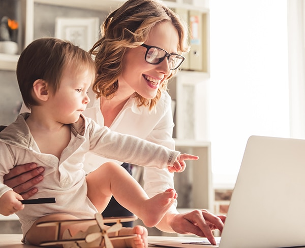 An image of a woman and a baby working on a laptop