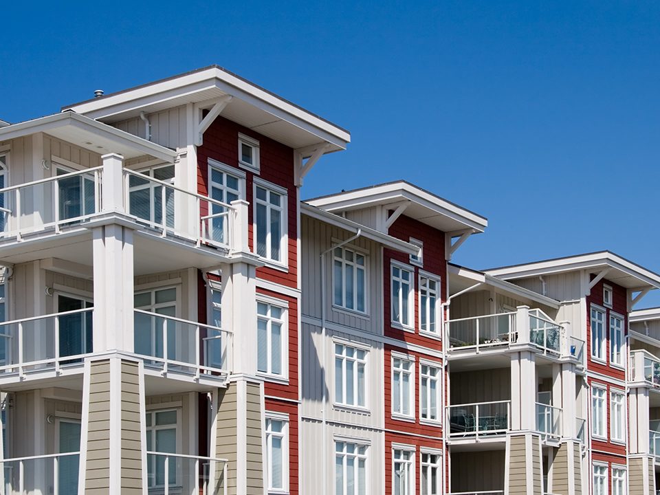 A stretch of blue sky over the top of a nice condo building.