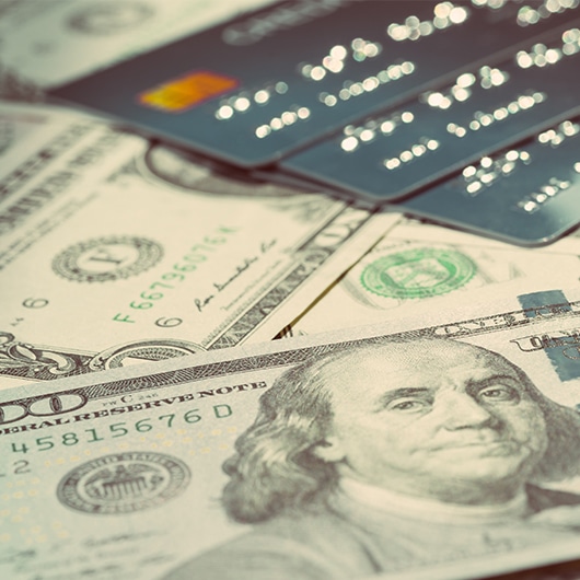 A stack of hundreds with a selection of credit cards on top.